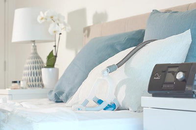 AirFit™ N30i mask sitting on bed attached to tubing and AirSense™ 10 device